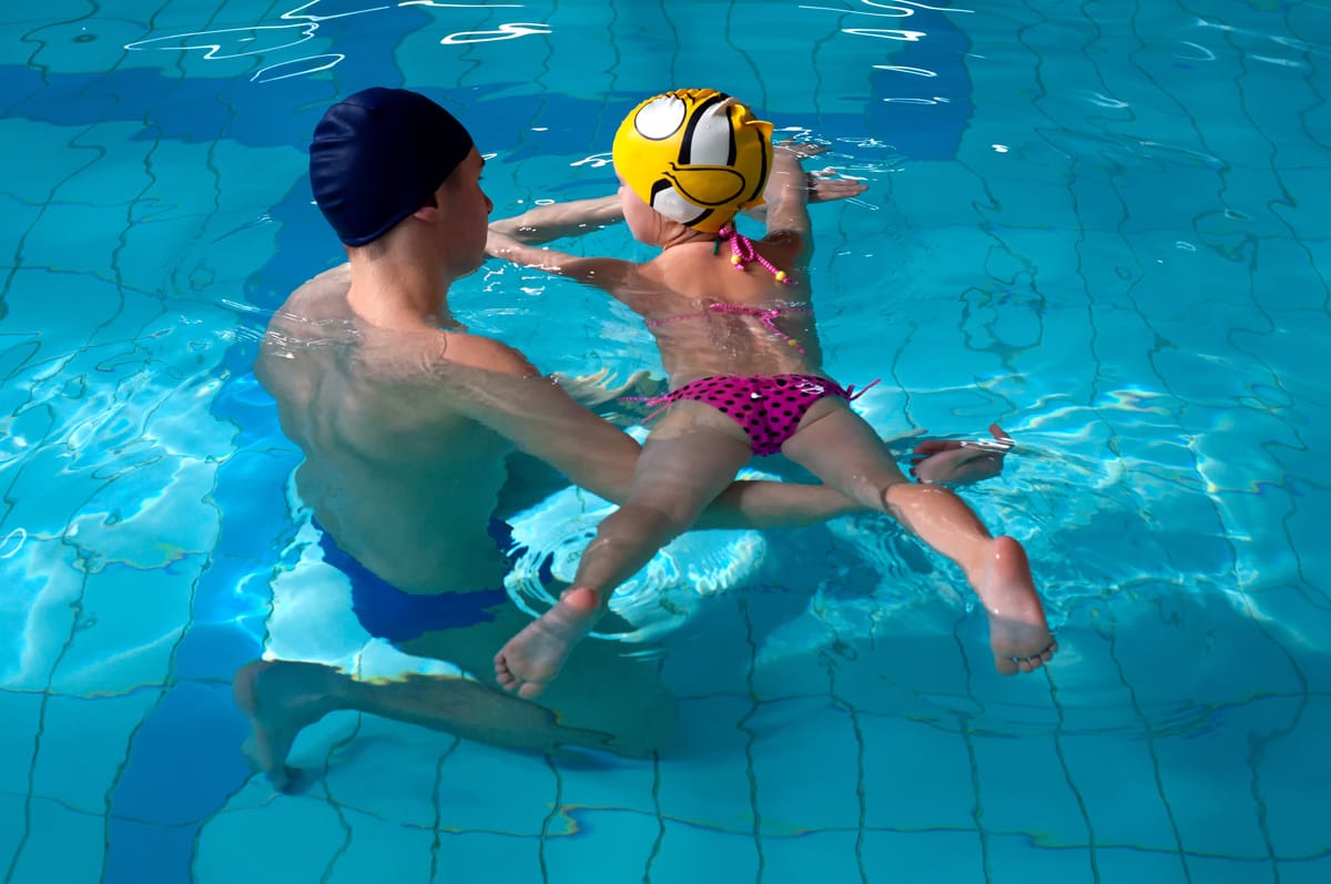 Swimming pool coach teaches a little girl to swim Extra zwemlessen